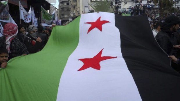 Protesters wave a large Syrian flag during the funeral of Jamal Hamdo Daqno, Subhi Haroon, and Akrma Muhammad Qutani, who protesters said were killed during clashes with government troops.