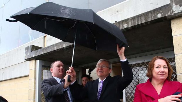 Prime Minister Kevin Rudd is assisted with his third umbrella by his protection team after two prevoius umbrellas blew out at the Hobart showgrounds in the seat of Deninson in Tasmania on Saturday.