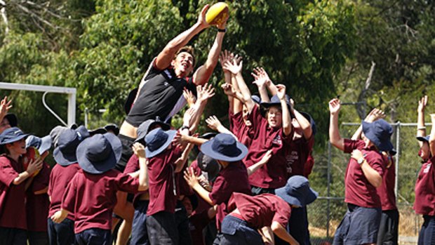 Justin Koschitzke flies for a mark over students from Tyabb Primary School.