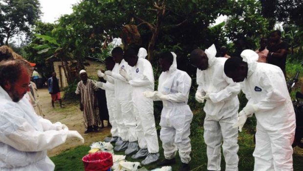 Volunteers prepare to remove the bodies of people who were suspected of contracting Ebola and died in the community in the village of Pendebu, north of Kenema, in Sierra Leone.
