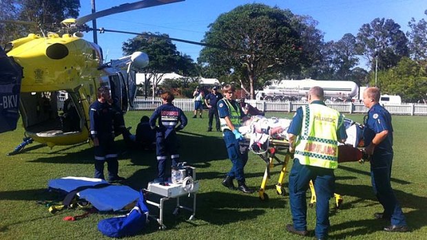 Paramedics take the injured cyclist to the RACQ CareFlight Rescue helicopter.