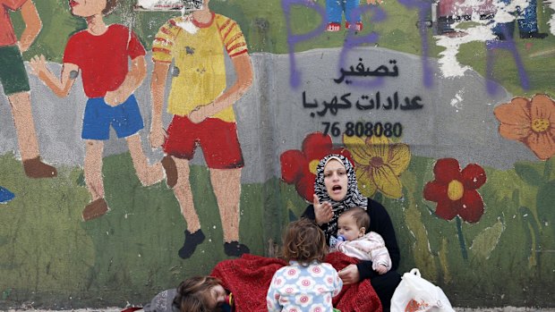 A Syrian woman sits begging with children on a street in Beirut.