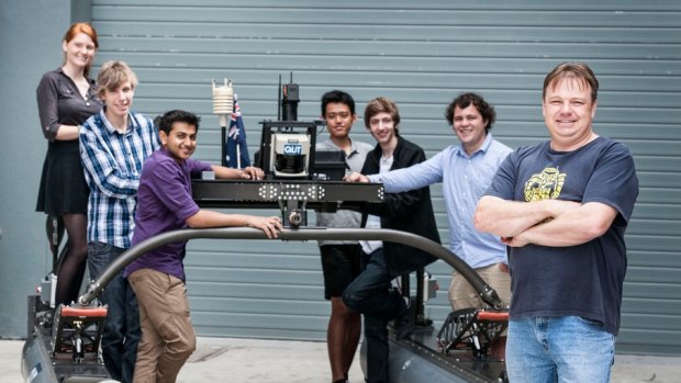 QUT students with Dr Bunbabin and their robot boat.