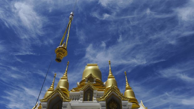 Hundreds of people attended a  ceremony at the Wat Dhammadharo Buddhist temple in Lyneham, where a crane lifted a golden tiered umbrella on to the main dome of the partly constructed pagoda.