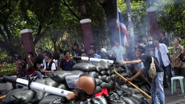 Anti-government protesters hold launchers behind their barricades at a road block  in Bangkok today.
