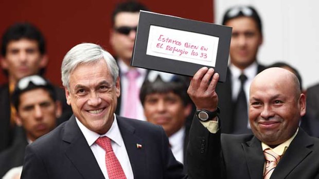 Chilean President Sebastian Pinera (left) presents miner Jose Ojeda with the framed note the miner wrote last year, which informed the world he and 32 colleagues were trapped. The presentation was made at a ceremony to mark the one-year anniversary of the cave-in.