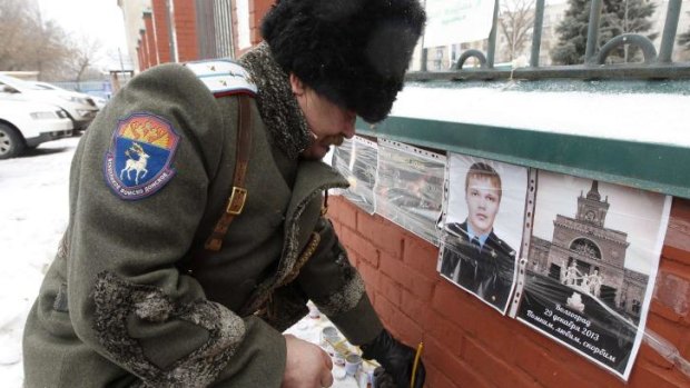 A Russian Cossack lights a candle near a photo of Russian police sergeant who was killed in a suicide bomb blast in the southern Russian city of Volgograd on December 29.