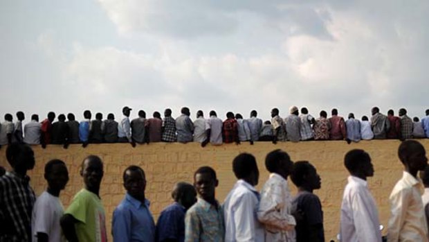 South Sudanese men queue while early birds sit on the wall of Juba's soccer stadium for the historic match.