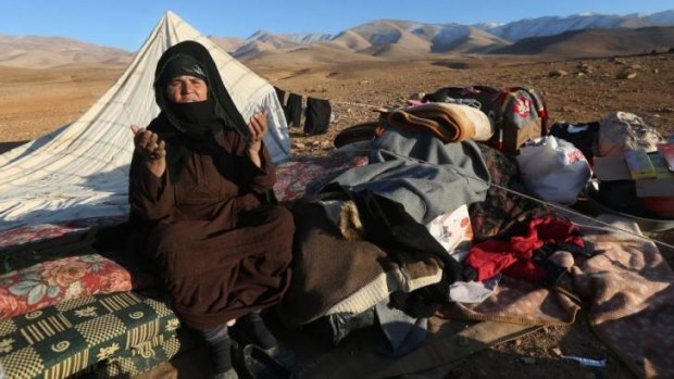Fears: A Syrian woman prays as she sits next to her belongings near Aarsal. Refugees there said they had been attacked by Syrian aircraft.