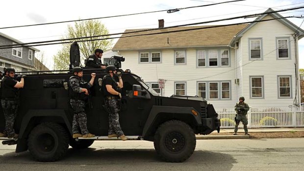 Manhunt: A police SWAT team search houses for the second of two suspects wanted in the Boston Marathon bombings.