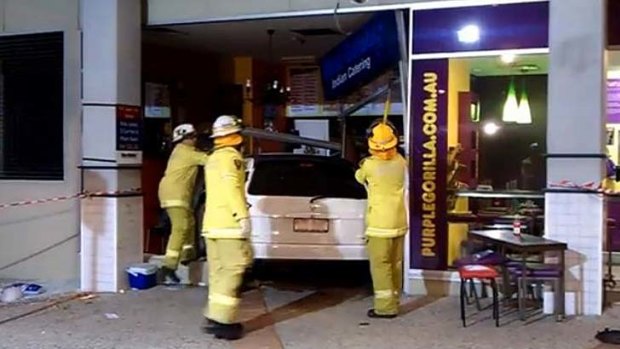 Fire fighters work around the vehicle which drove into a Woolloongabba restaurant.