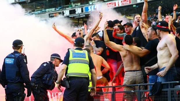 Fired up: Wanderers fans in the crowd let off flares as police officers look on during Saturday's match at  Etihad Stadium.