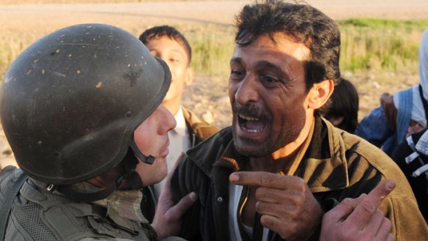 A Syrian argues with a Turkish soldier while trying to cross the border during a bombardment that killed 18 people.
