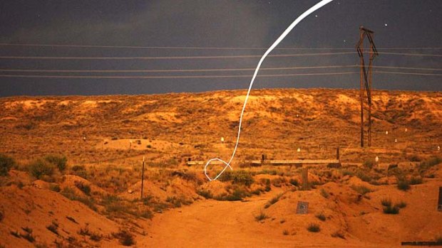 A time exposure, a light-emitting diode, or LED, attached to a self-guided bullet shows a bright path during a nighttime field test.