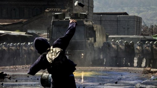 A protester clashes with riot police as activists take part in a demonstration in Santiago.