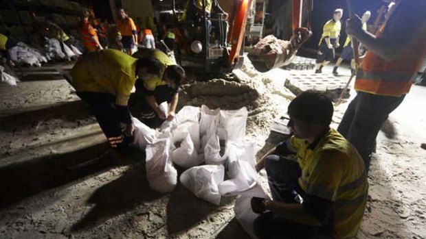Wave of dread ... volunteers at the council depot in the Brisbane suburb of Stafford prepare sandbags late last night.