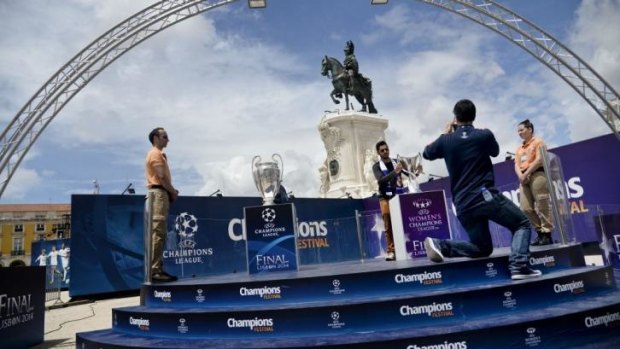 A Real Madrid supporter poses with the men's UEFA Champions League trophy at Terreiro do Paco square in Lisbon on Thursday.