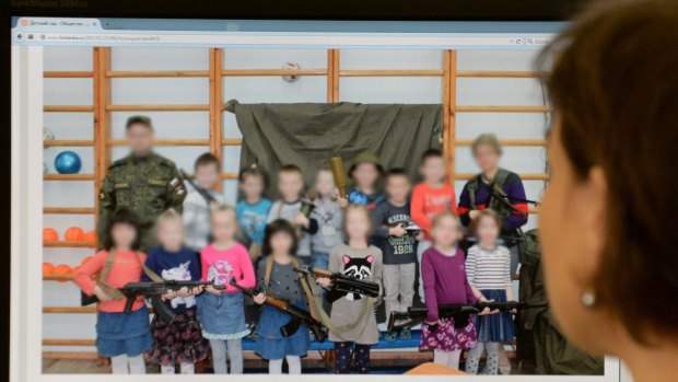 Controversy ... A Moscow woman looks at a computer screen displaying a photo that shows boys and girls around five or six years-old posing with weapons that include machine guns, a grenade launcher and a sniper rifle at a kindergarten in Saint Petersburg. 