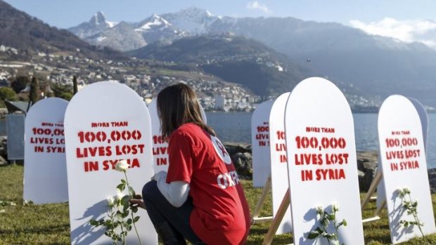 A member of the aid charity Oxfam puts a white rose on  symbolic gravestones at the Geneva II peace talks on Syria in Montreux on Wednesday.