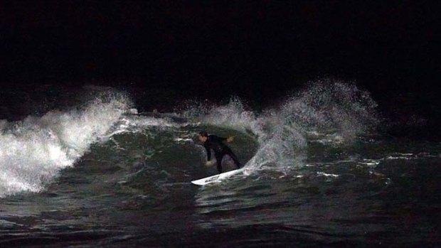 Lighting up the ocean ... Ian Wallace surfs at Bondi Beach last night. Picture by Eugene Tan of <a href= "http://www.aquabumps.com"><b>Aquabumps.com</b></a>