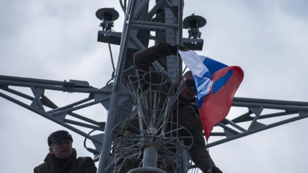 Men hang up a Russian flag on a seized Ukrainian corvette Khmelnitsky in Sevastopol, Crimea.
