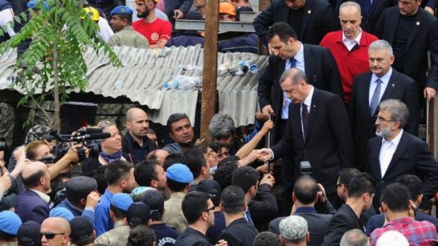 Turkey's Prime Minister Recep Tayyip Erdogan walks down steps, front row left, is surrounded by security members as he visits the coal mine in Soma, western Turkey.