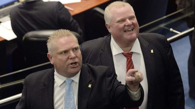 Toronto city councillor Doug Ford (left) and his brother, Mayor Rob Ford (left) react to the gallery after the mayor and an unidentified member of his staff captured images of the gallery during a special council meeting at City Hall in Toronto.
