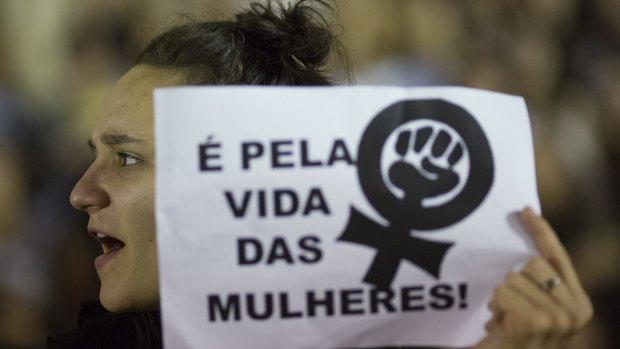 A demonstrator holds a sign that reads in Portuguese "For the lives of women!" during a protest against the gang rape of a 16-year-old girl.