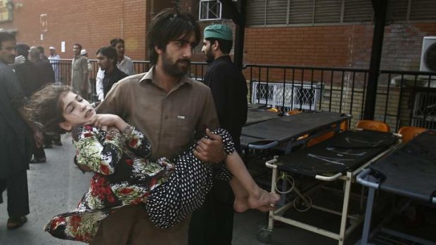 Vaccination program suspended: A man carries a girl who was injured in a bomb blast that targeted police protecting polio vaccination workers.