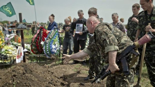 Rising toll ... A pro-Russian rebel throws dirt on the grave of a member of military-patriotic group 'Kaskad' who was killed Monday during clashes with Ukrainian troops, during his funeral in Luhansk, eastern Ukraine.