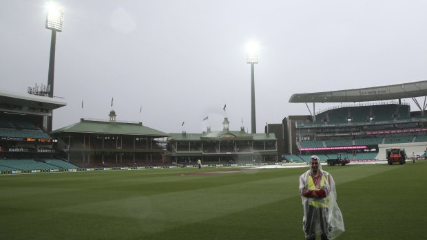 A security guard stands on the field at the Sydney Cricket Ground as play is abandoned due to inclement weather during a miserable rain-affected day two of the third Test between Australia and the West Indies.