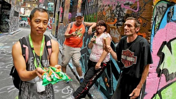 Chito Javier from Youth Projects gives icy-poles to homeless people (from left) Koos, Lisa and Paul.