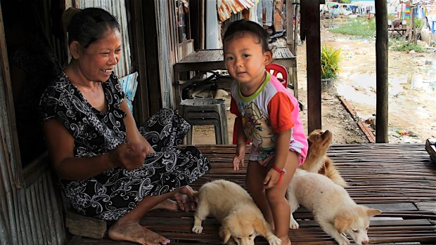 A woman plays with a child in Khmounh, Cambodia, where dozens of women have signed surrogacy agreements to bear children for foreigners.