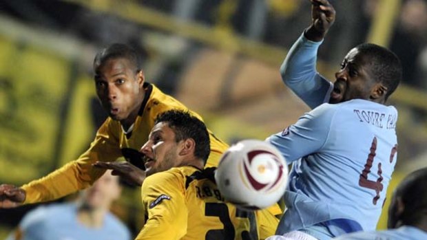 Ricardo Fatty (L) and Raul Bobadilla of Aris contest possession with Yaya Toure of Manchester City.