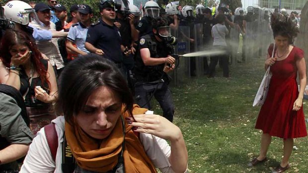 A riot policeman sprays Ceyda Sungur in the face.