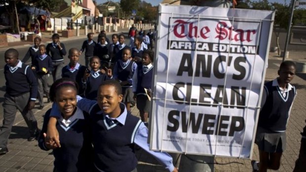 Schoolchildren walk past a newspaper placard reporting the election victory of Jacob Zuma's African National Congress (ANC) party.