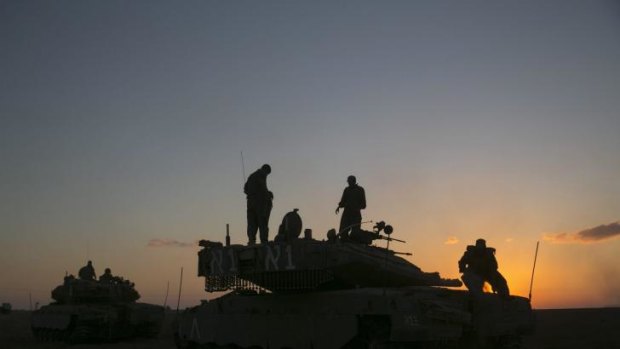 Israeli soldiers stand on top of a tank near the Israeli border with the Gaza Strip on August 2.