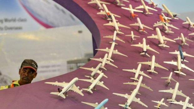A worker peers out at the side of various airlines models on display at the exhibition centre ahead of the Singapore's Airshow.