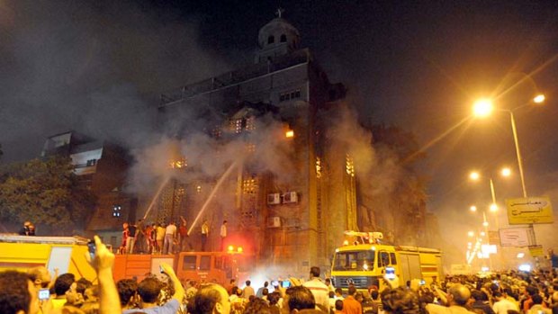 Egyptians gather as firefighters extinguish a fire on a church after clashes between Muslims and Christians in Cairo.