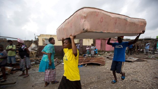 Residents carry a mattress to a shelter after homes were destroyed by Hurricane Matthew in Les Cayes, Haiti.