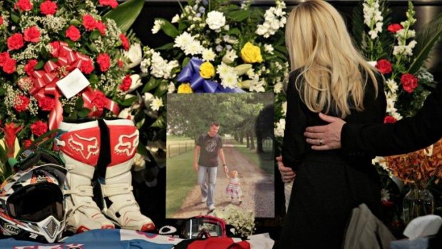 Nicole Oulson looks at a photo of her husband Chad and their daughter Alexis, along with her husband's helmets and motocross gear, on display during a memorial service at the Land O'Lakes Church of God.