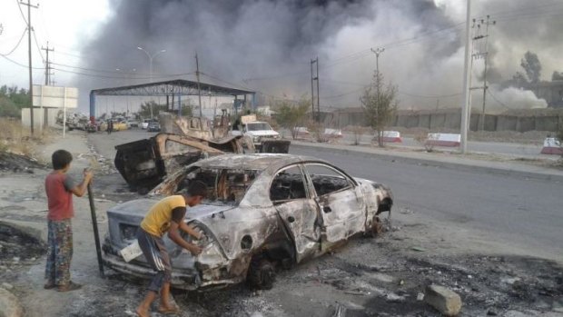 Children stand next to a burnt-out vehicle during clashes between Iraqi security forces and IS militants in Mosul.