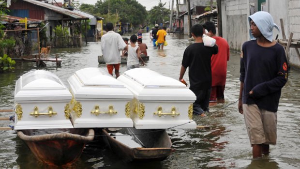 A boatman tows empty coffins through the flooded streets on the edge of Laguna Lake, east of Manila.