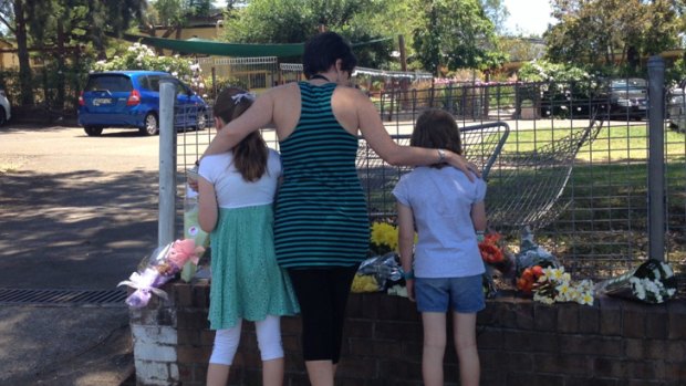 A mother and two of her children from Carlingford Public School leave flowers at the site of the crash.