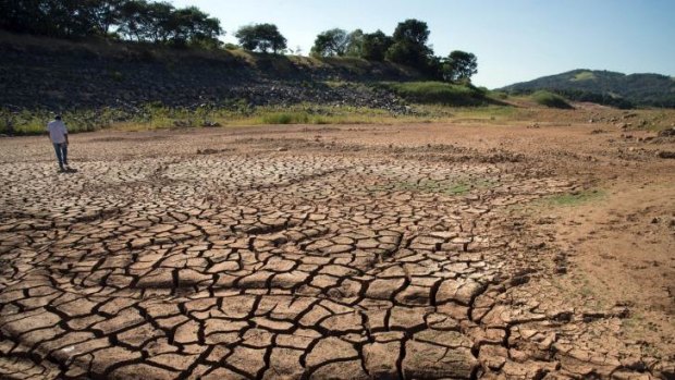 A man walks on dry, cracked earth where water usually stands at the Jaguari Reservoir in the state of Sao Paulo.
