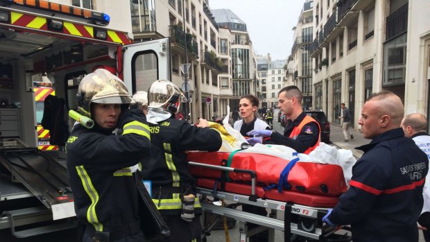 Firefighters carry an injured man on a stretcher from the offices of the French satirical newspaper <i>Charlie Hebdo</i> in Paris after armed gunmen stormed its offices and opened fire.