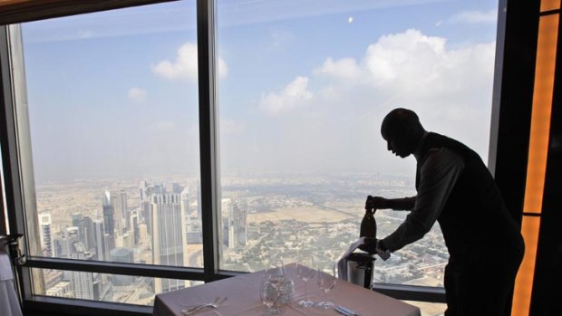 Bar captain Solomon from Kenya places a bottle of champagne at At.mosphere, the world's highest restaurant in the Burj Khalifa in Dubai.