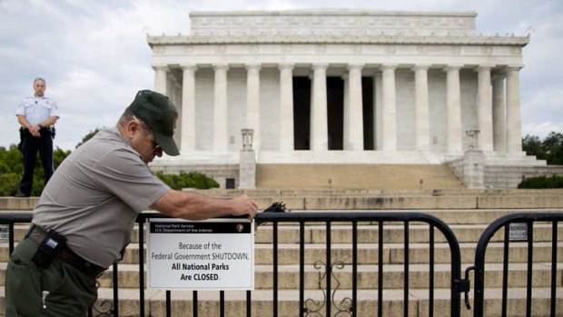 A US Park Police officer watches at left as a National Park Service employee posts a sign on a barricade closing access to the Lincoln Memorial in Washington. About 800, 000 federal workers have been suspended across the US.