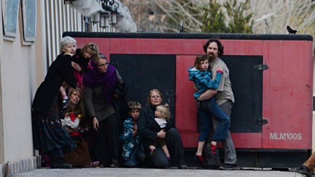 Foreigners hold children as they take refuge behind a generator outside a guesthouse during an attack by Taliban gunmen in Kabul. 