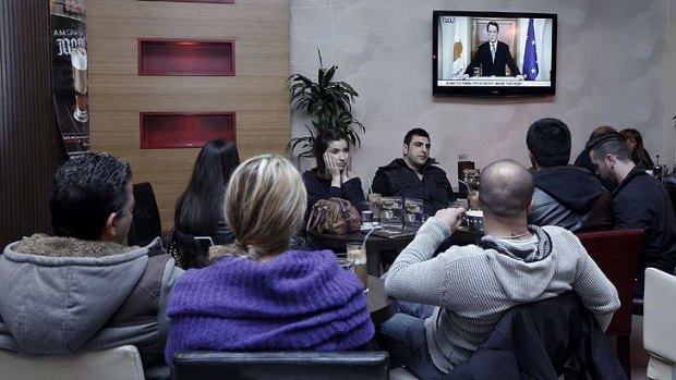 After the deal ... people watch as Cyprus' President Nicos Anastasiades addresses the nation at a cafeteria in Nicosia.